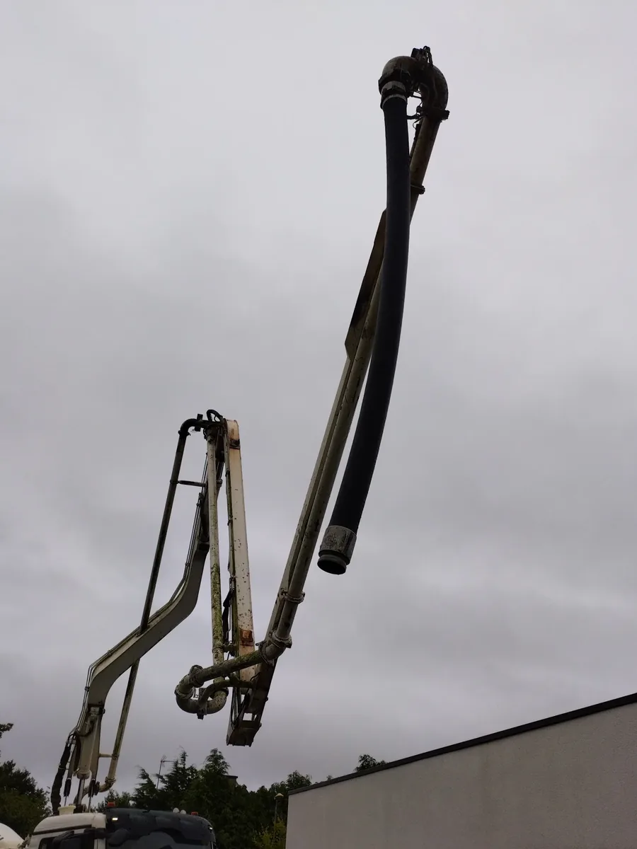 Bras articulé d'un camion pompe à béton déplié au-dessus du toit d'une maison