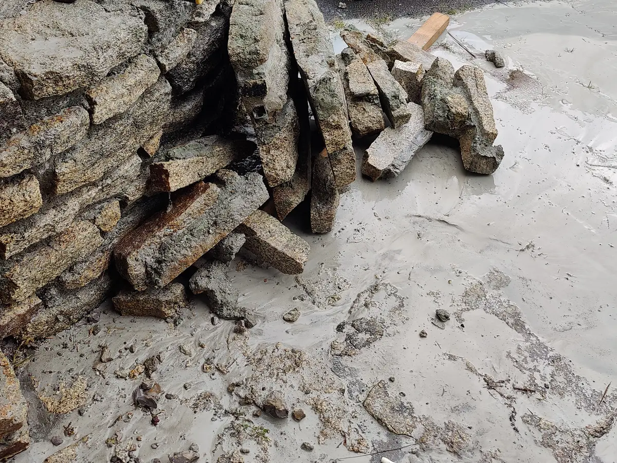 Pierres de granit déposées une à une et rangées au pied du mur après découpe