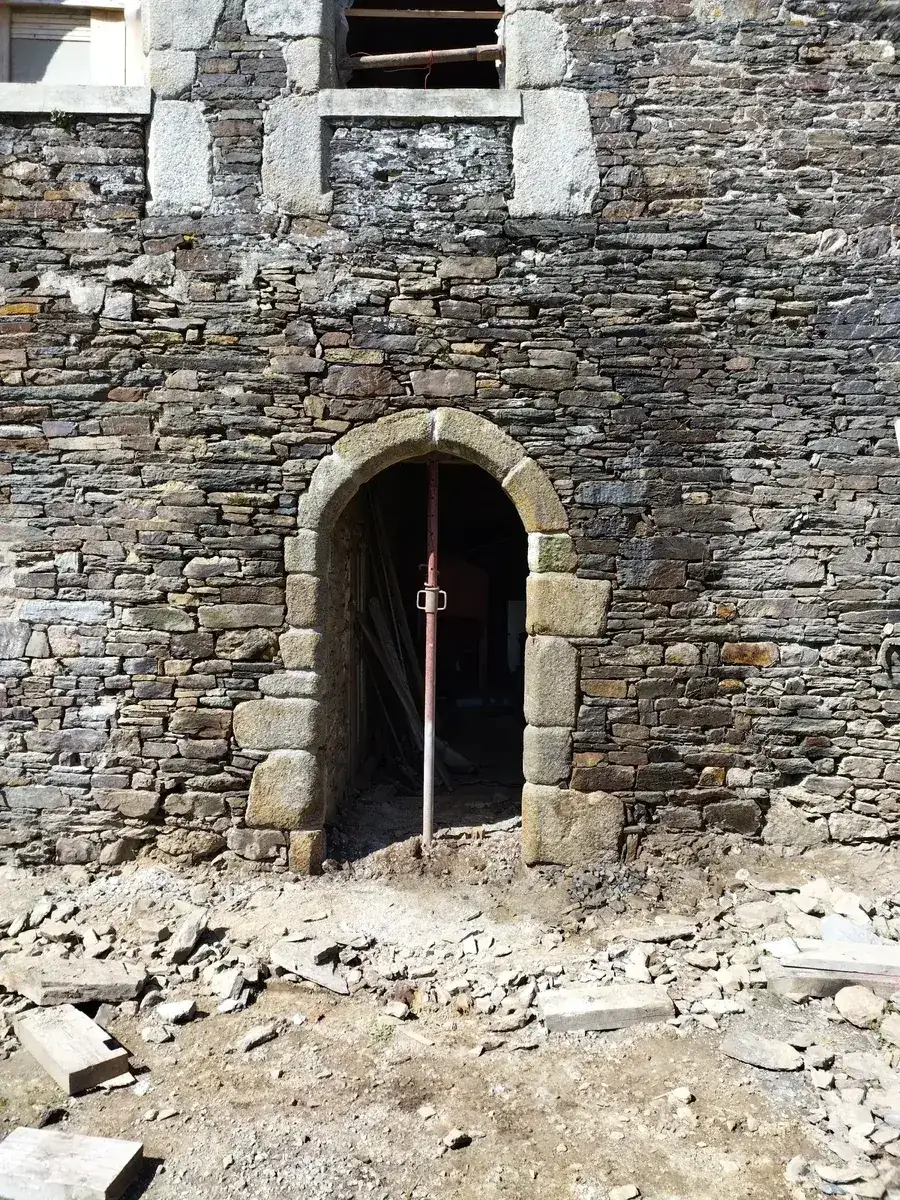 Encadrement de porte cintré en pierre de taille terminé dans un mur de schiste