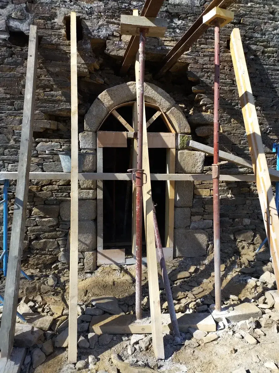 Porte cintrée en granit étayée par des étais et madriers avant dépose
