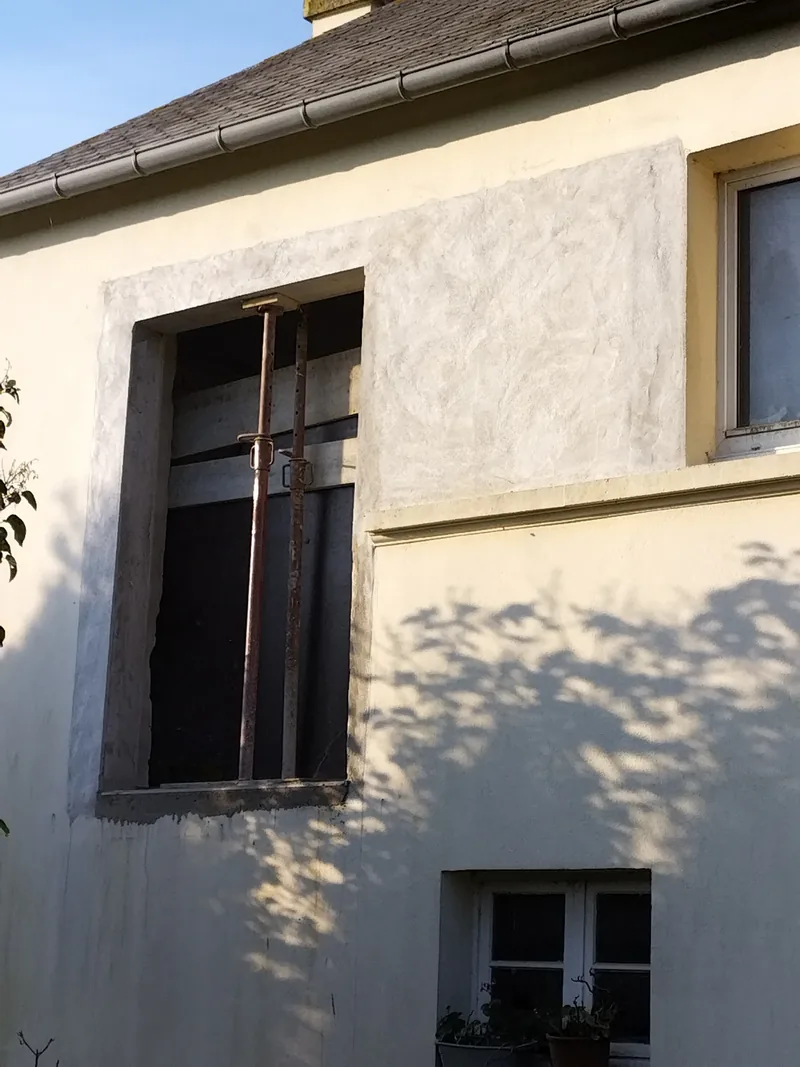 Nouvelle fenêtre créée dans une façade enduite, étai en place et enduit repris au-dessus
