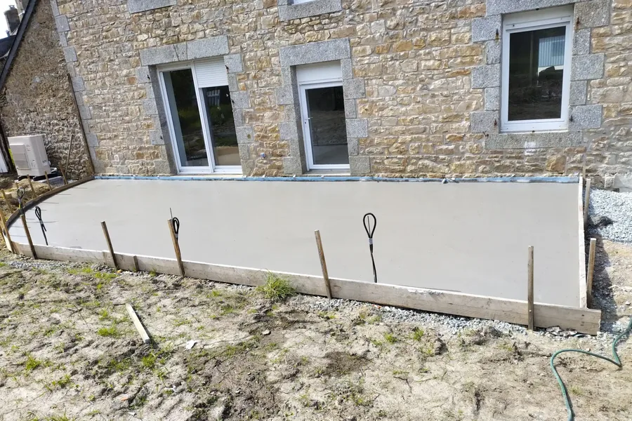 Longue dalle de terrasse coulée le long de la façade en pierre, coffrage bois encore en place